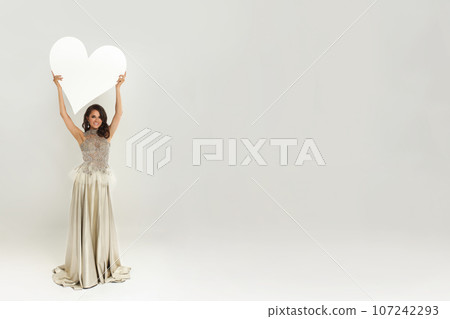Perfect happy fashion model woman in luxurious dress holding empty white banner board Perfect happy fashion model woman in luxurious dress holding empty white banner board 107242293