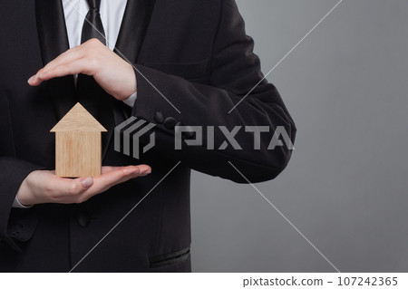 Hand holding wooden home model. Real estate insurance and property concept 107242365
