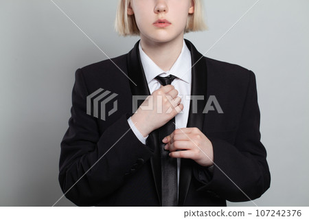 Woman putting on a tie on white background, closeup fashion portrait 107242376