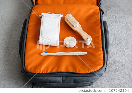 Plastic free travel, traveling sustainably. How to use less plastic on holiday. Eco Friendly Travel Products in orange suitcase. 107242394
