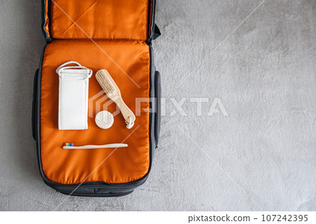 Plastic free travel, traveling sustainably. How to use less plastic on holiday. Eco Friendly Travel Products in orange suitcase. 107242395