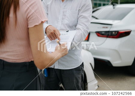 Customers and car insurance agents have entered into agreements and signed documents to claim compensation after on the road in sun light.. Customers and car insurance agents have entered into agreements and signed documents to claim compensation after on the road in sun light.. 107242566
