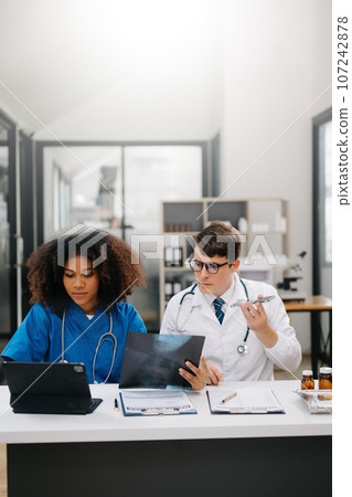 Doctor Talks With Professional Head Nurse or Surgeon, They Use Digital tablet Computer. Diverse Team of Health Care Specialists Discussing Test Result on desk in hospital . 107242878