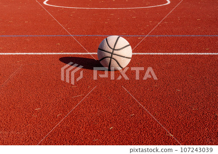 A well worn basketball ball on empty court A well worn basketball ball on empty court 107243039