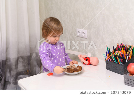 a little girl looks at a plate of food, she wonders what she was poured to eat. a little girl looks at a plate of food, she wonders what she was poured to eat. 107243079
