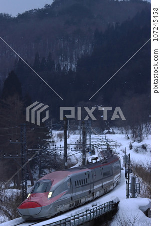 E6 Shinkansen going down a mountain pass with snowy mountains in the background_Photographed on February 26, 2022 107245458