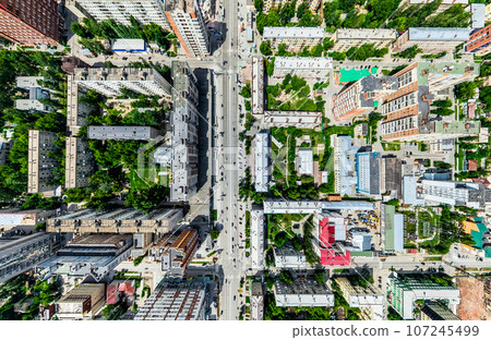 Aerial city view with crossroads and roads, houses, buildings, parks and parking lots. Sunny summer panoramic image Aerial city view with crossroads and roads, houses, buildings, parks and parking lots. Sunny summer panoramic image 107245499