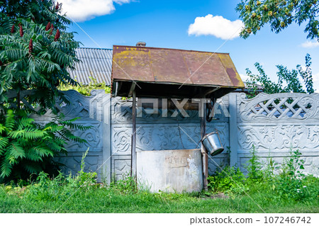 Old well with iron bucket on long forged chain for clean drinking water Old well with iron bucket on long forged chain for clean drinking water 107246742