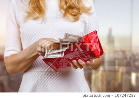 Close up womens hands open a red wallet with money. Counting money banknotes. 107247282