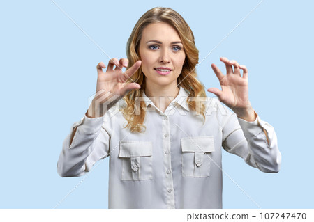 Portrait of businesswoman zooming in a tranparent virtual screen for copy space. Isolated on blue background. Portrait of businesswoman zooming in a tranparent virtual screen for copy space. Isolated on blue background. 107247470