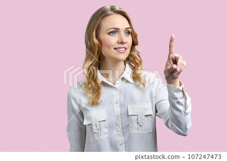 Business woman is touching an invisible virtual screen. Isolated on pink background. 107247473