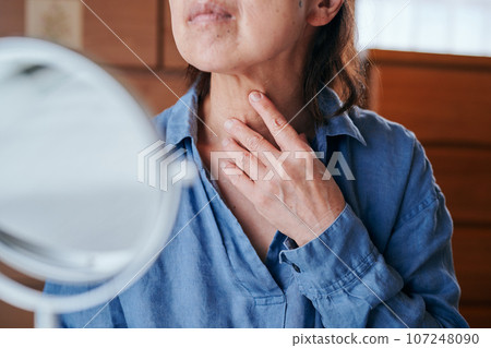 老婦人對著鏡子檢查脖子上的皺紋 107248090