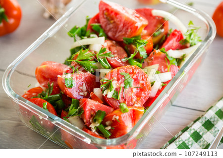 Spicy snack tomatoes with garlic, herbs, seasonings and onions in a glass bowl . 107249113