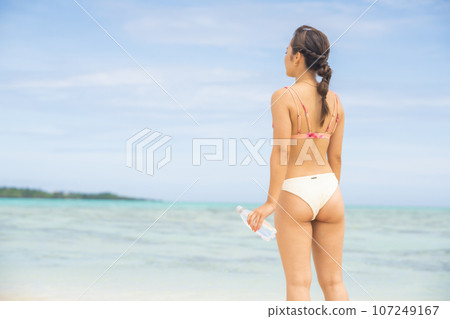 A young woman holding mineral water on the beach No face A young woman holding mineral water on the beach No face 107249167