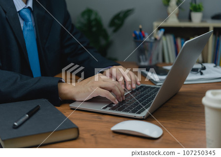 man sitting at a desk, typing on a laptop keyboard computer. of online connectivity and job search in our personal. as technology, social media, online marketing, and education. man sitting at a desk, typing on a laptop keyboard computer. of online connectivity and job search in our personal. as technology, social media, online marketing, and education. 107250345