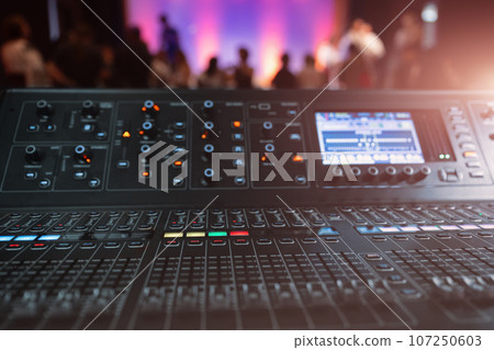 Live theater concert show sound video music control console with scene lights background. Sound engineer mixer soundboard equipment with many knobs, buttons, faders, equalizer screen and light Live theater concert show sound video music control console with scene lights background. Sound engineer mixer soundboard equipment with many knobs, buttons, faders, equalizer screen and light 107250603