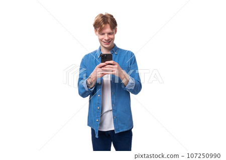 a young caucasian guy with short red hair enters data into a smartphone. e-business concept a young caucasian guy with short red hair enters data into a smartphone. e-business concept 107250990