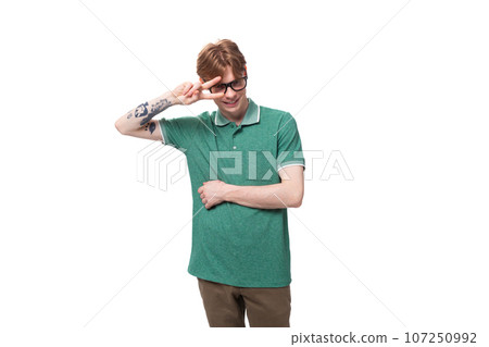 young stylish cheerful european guy with red hair with a tattoo on his forearm wears a green t-shirt young stylish cheerful european guy with red hair with a tattoo on his forearm wears a green t-shirt 107250992