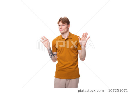 young charming redhead man dressed in a mustard t-shirt on a white background 107251071