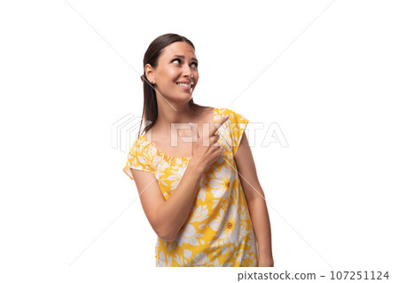 Caucasian young woman with straight black hair dressed in a yellow sundress gesturing with her Caucasian young woman with straight black hair dressed in a yellow sundress gesturing with her 107251124