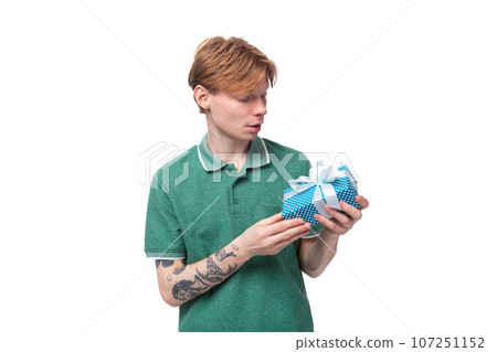 young red-haired caucasian guy in a green t-shirt is going to received a gift for his holiday young red-haired caucasian guy in a green t-shirt is going to received a gift for his holiday 107251152
