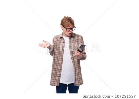 handsome caucasian student guy in glasses is trying to figure out the phone 107251557