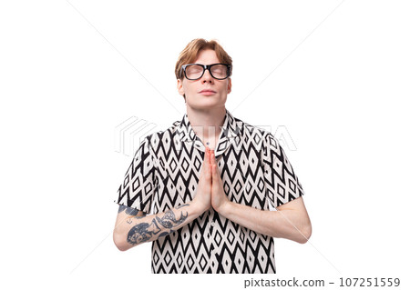 young european male student with red hair dressed in a shirt with a diamond pattern shows 107251559