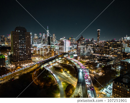 Evening in modern urban borough in metropolis. glowing high rise buildings and heavy traffic on multilane roads. Colourful city lights. New York City, USA 107251901