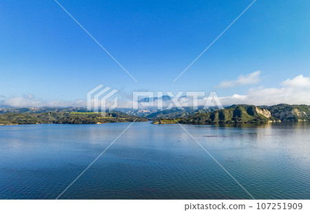 Aerial panoramic shot of lake water surface and mountains shrouded in clouds in distance. Amazing landscape photo. Cachuma Lake, California, USA 107251909