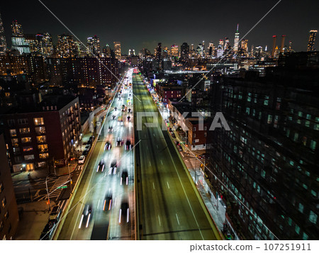 Motion blurred aerial shot of traffic on busy multilane expressway in night metropolis. Downtown skyscrapers in background. New York City, USA 107251911