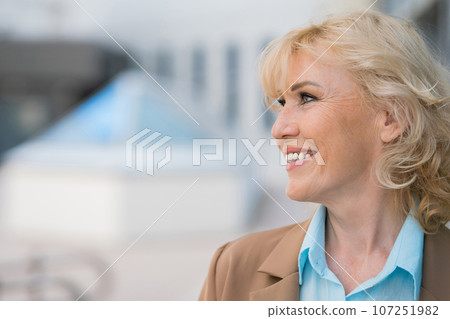 Mature woman with happy expression against company building Mature woman with happy expression against company building 107251982