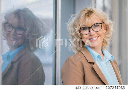 Mature woman in glasses looks with delighted expression Mature woman in glasses looks with delighted expression 107251983