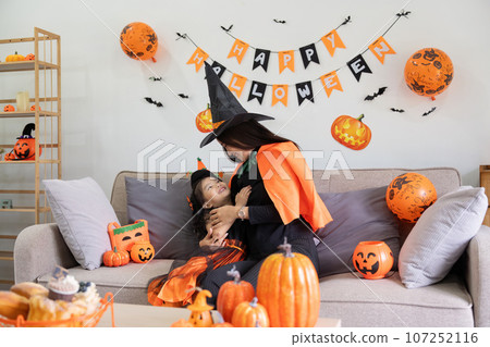 Happy family mother and child happy girl with Halloween at home together beautifully decorated Happy family mother and child happy girl with Halloween at home together beautifully decorated 107252116