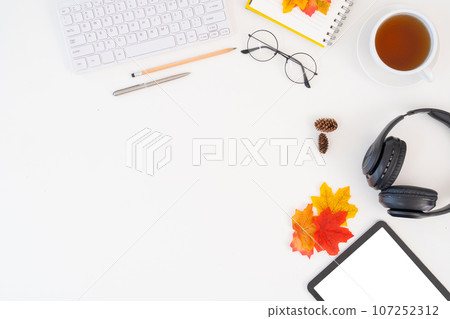 Top view above of desk workspace with blank copy space mockup, headphones, coffee cup, leaves on autumn background. top view work seasonal autumn concept 107252312