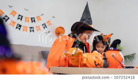 Happy family mother and child happy girl with Halloween at home together beautifully decorated Happy family mother and child happy girl with Halloween at home together beautifully decorated 107252418