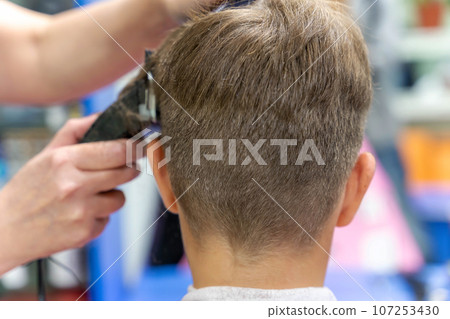 Hair cutting for a child using a hair clipper in a beauty salon Hair cutting for a child using a hair clipper in a beauty salon 107253430