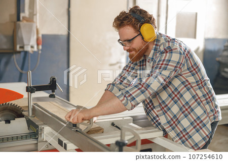 Woodworker sawing a board with a circular saw in a carpentry workshop. High quality photo Woodworker sawing a board with a circular saw in a carpentry workshop. High quality photo 107254610