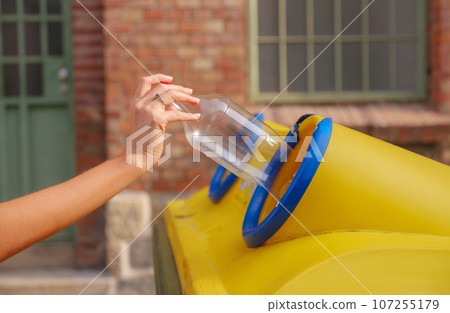 woman throwing plastic bottle Recycling bin stand on european street. Waste separation rubbish before drop to garbage bin to save world, environment care. Pollution trash recycling management concept 107255179