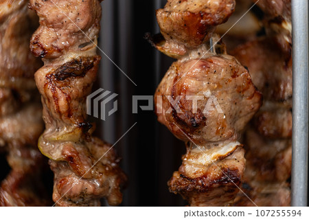 Cooking pork meat in an electric kebab maker on vertical skewers Cooking pork meat in an electric kebab maker on vertical skewers 107255594