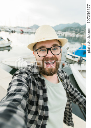 Traveller millennial man taking selfie of luxury yachts marine during sunny day - travel and videocall and blogging concept Traveller millennial man taking selfie of luxury yachts marine during sunny day - travel and videocall and blogging concept 107256877