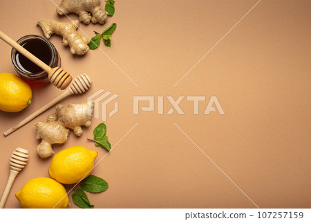 Orange detox drink, lemons, mint, ginger, honey in glass jar, honey wooden dippers top view. Food for immunity stimulation and against flu. Healthy remedies to boost immune system, copy space 107257159