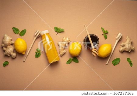 Composition with detox drink, lemons, mint, ginger, honey in glass jar and honey wooden dippers top view. Food for immunity stimulation and against flu. Healthy natural remedies to boost immune system 107257162