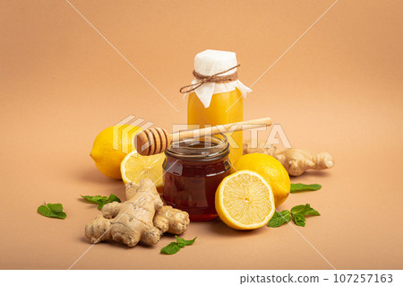 Composition with detox drink, sea buckthorn berries, lemons, mint, ginger, honey in glass jar. Food for immunity stimulation and against flu. Healthy natural remedies to boost immune system Composition with detox drink, sea buckthorn berries, lemons, mint, ginger, honey in glass jar. Food for immunity stimulation and against flu. Healthy natural remedies to boost immune system 107257163