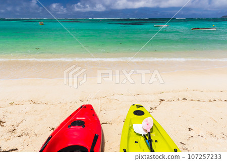Colorful plastic kayaks lay on a beach on a sunny day Colorful plastic kayaks lay on a beach on a sunny day 107257233
