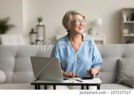 Positive elder retired woman in stylish glasses calculating income Positive elder retired woman in stylish glasses calculating income 107257527