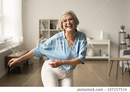 Joyful happy retired woman in glasses having fun at home 107257534