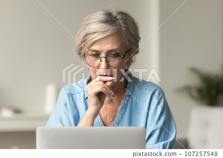 Focused senior business woman in glasses thinking on work problem Focused senior business woman in glasses thinking on work problem 107257548