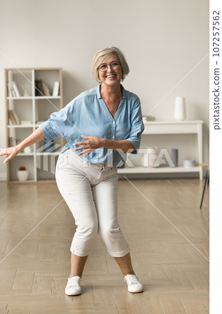 Cheerful carefree active retired woman dancing at home 107257562