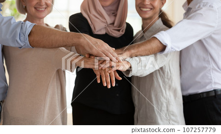 Diverse businesspeople stacked palms together showing unity and amity Diverse businesspeople stacked palms together showing unity and amity 107257779