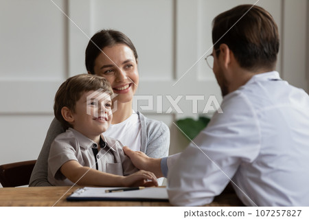 Friendly pediatrician touching smiling little patient shoulder, expressing support Friendly pediatrician touching smiling little patient shoulder, expressing support 107257827